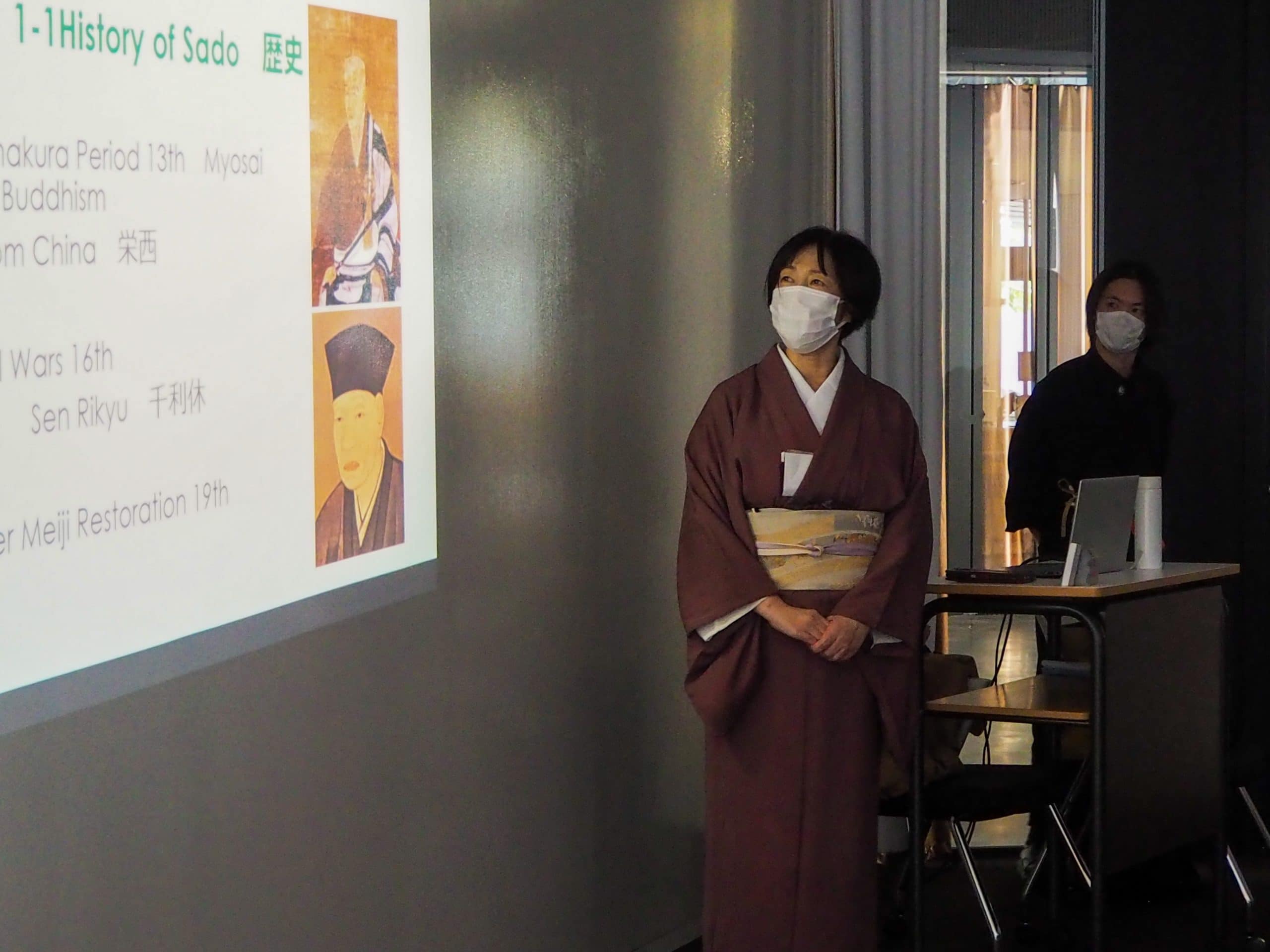 A teacher in a classroom explaining the history of Japanese tea ceremony