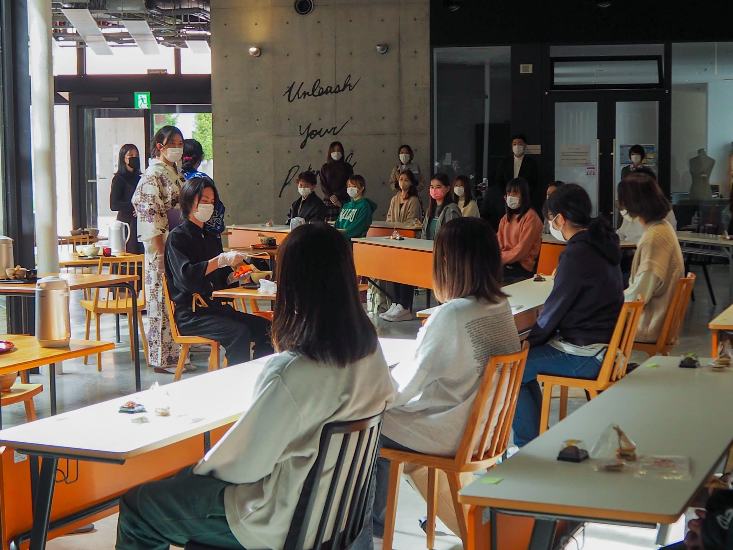 A student performs Japanese tea ceremony in front of a crowd 