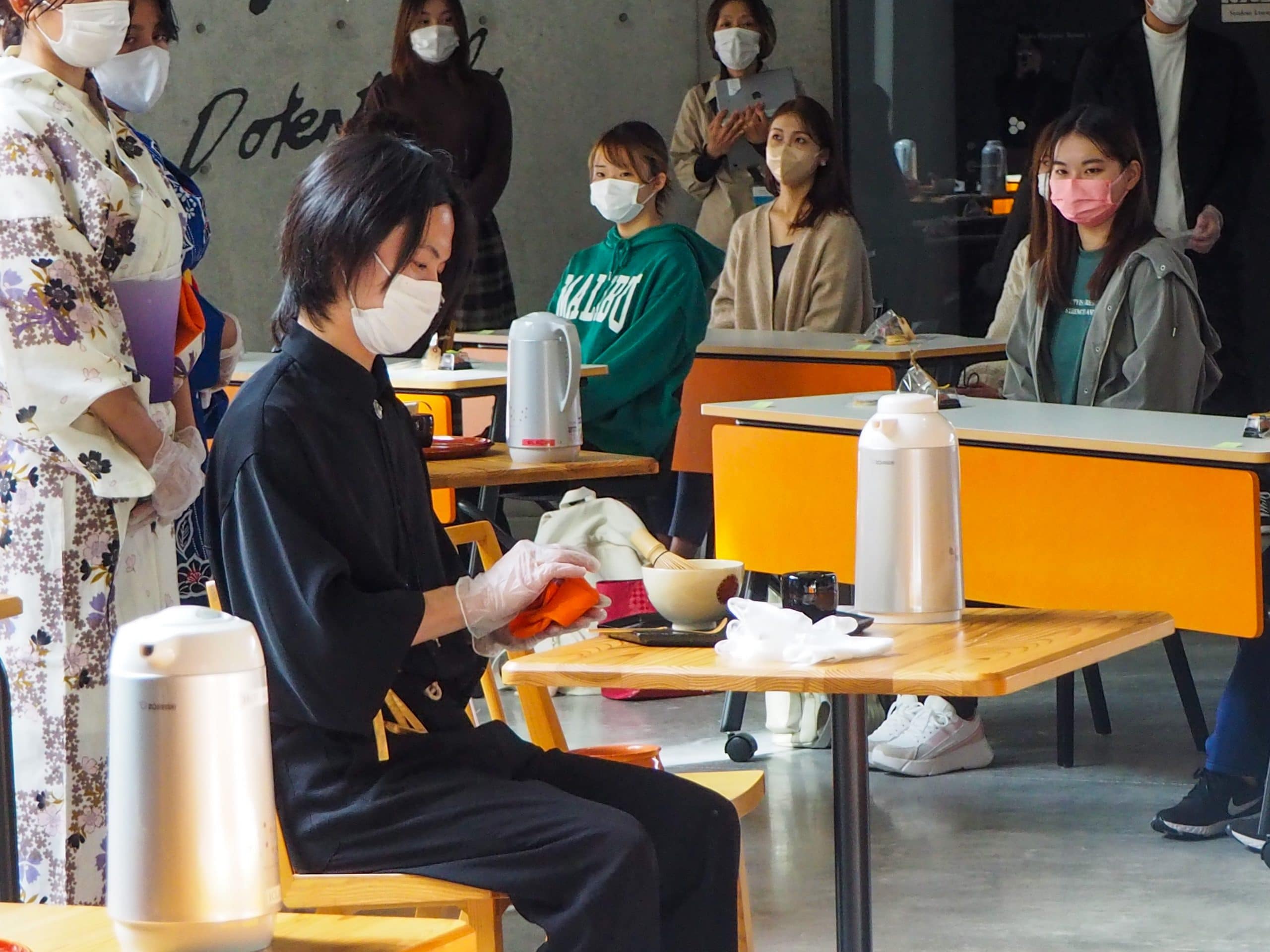 A student in traditional tea ceremony clothing performs Japanese tea ceremony in front of an audience