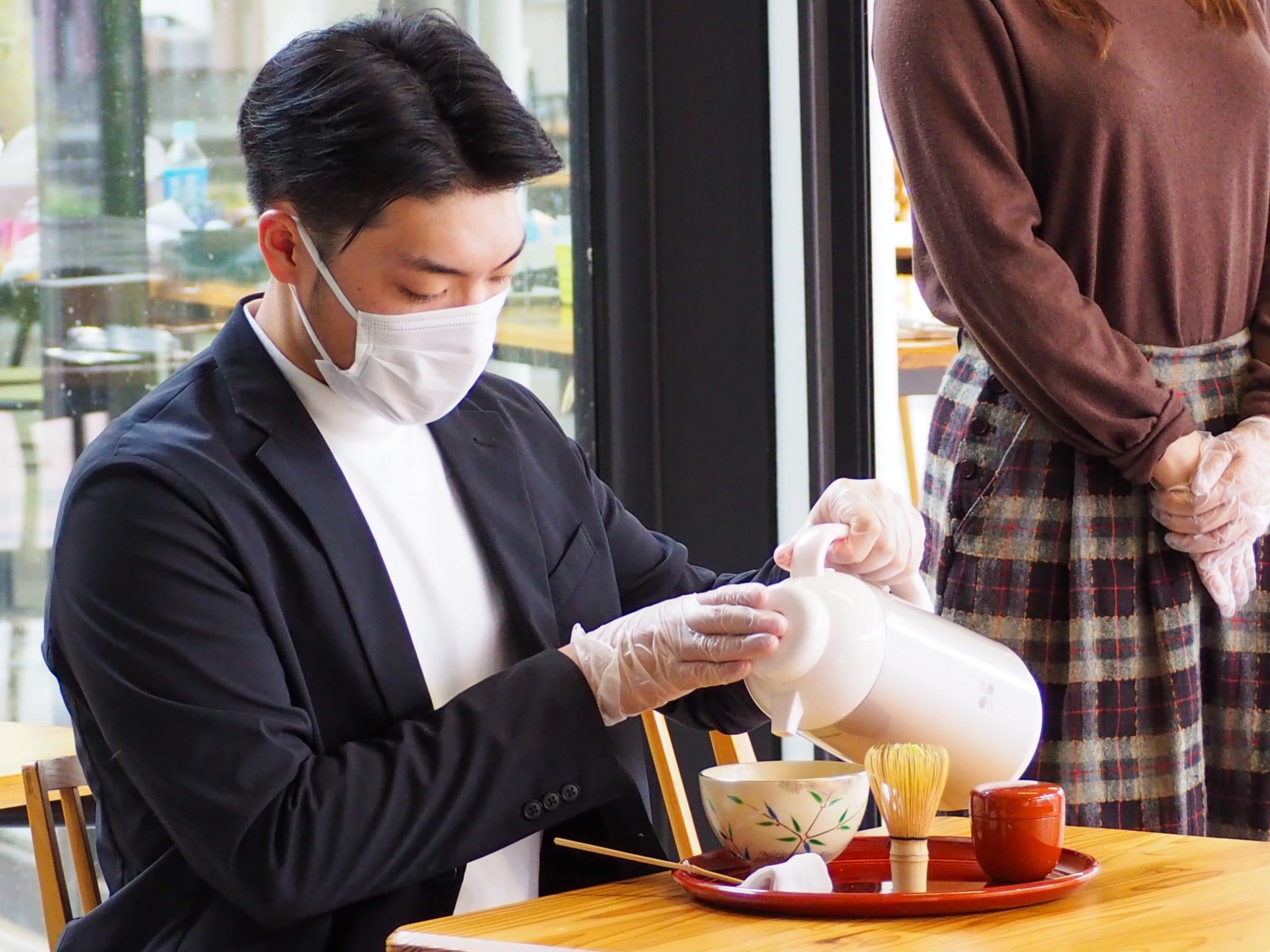 A student pours hot water into tea cup for tea ceremony