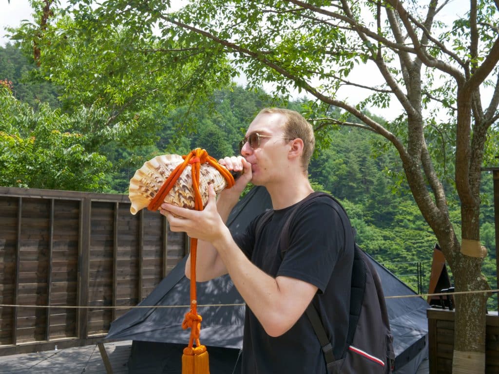 iCLA student tries blowing the conch shell, a ritual article commonly used in Shugendo 