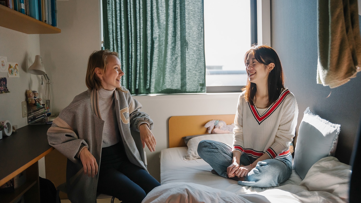 Two female iCLA students chatting in dorm room