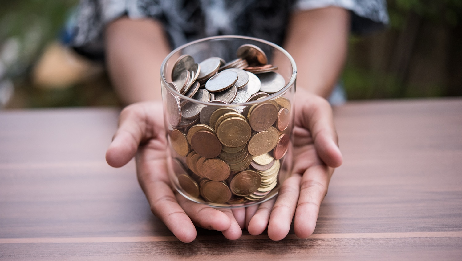 Hand putting coins in a jar