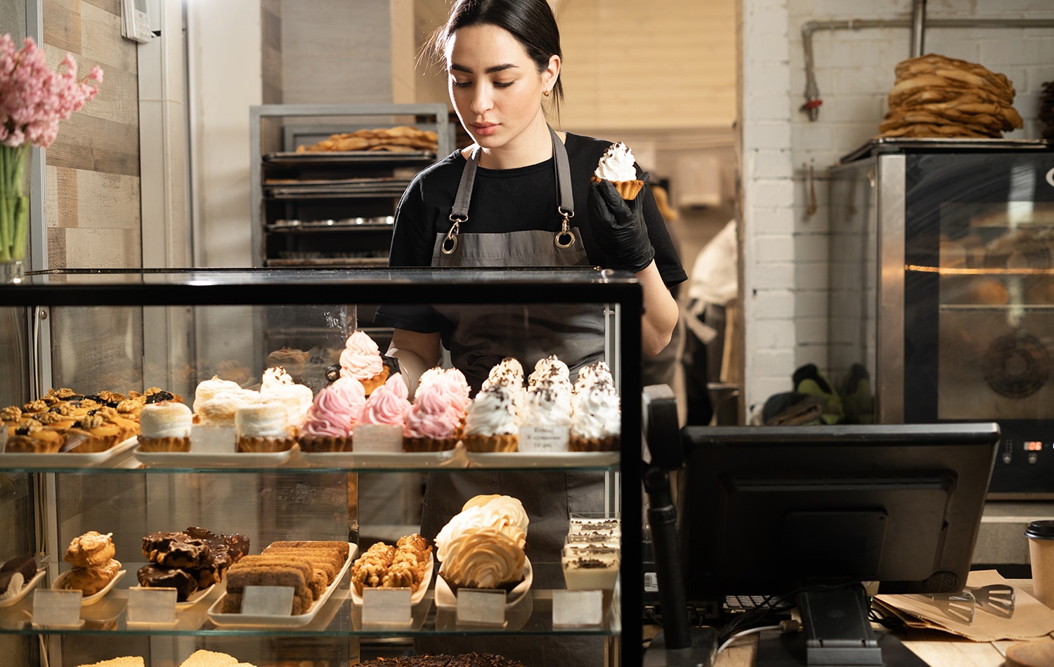 Woman working in a cafe holding a cup cake