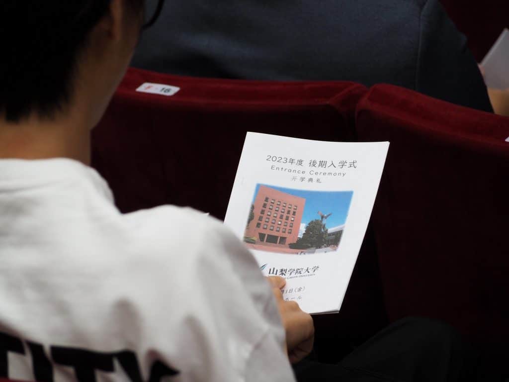 An iCLA Student holds the pamphlet for the Yamanashi Gakuin University Fall 2023 Entrance Ceremony