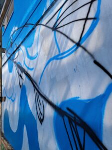 Gaku Okata's public mural is a work in progress. The outline of a trout can be seen on a blue background.