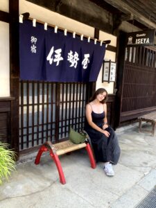 iCLA student sits in front of a traditional-looking shop in Narai Juku.