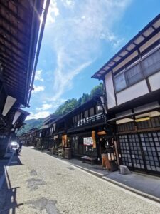 Traditional Japanese buildings line both sides of a small street in Narai Juku. There are no cars or telephone poles.