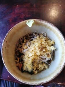 A hearty bowl of tanuki soba sits on a counter.