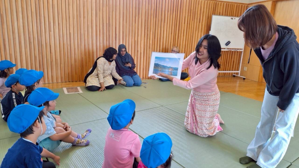 Yamanashi Gakuin Kindergarten students look at a picture held up by an iCLA international student to learn about cultural exchange.