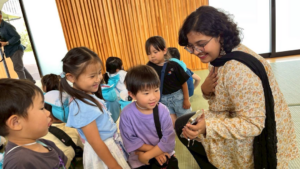 Yamanashi Gakuin Kindergarten children learning about cultural exchange excitedly look at a phone with an iCLA international student.