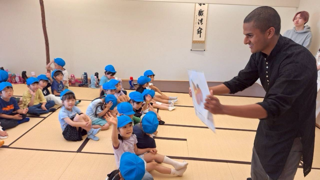 Yamanashi Gakuin Kindergarten students look at a picture held up by an iCLA international student.