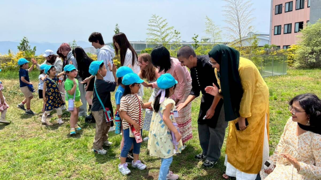 iCLA students high five kindergartners from the Yamanashi Gakuin Kindergarten in a line.