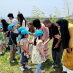 iCLA students high five kindergartners from the Yamanashi Gakuin Kindergarten in a line.