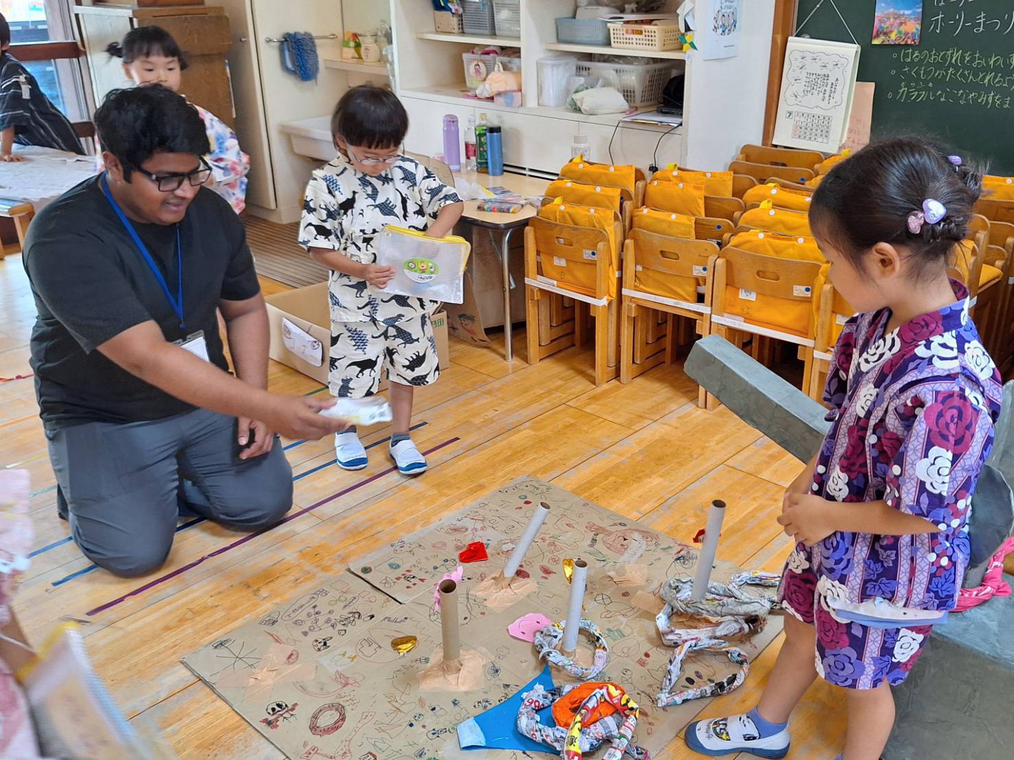 An iCLA student playfully tosses a ring at a ring toss booth made by Yamanashi Gakuin Kindergarten children.