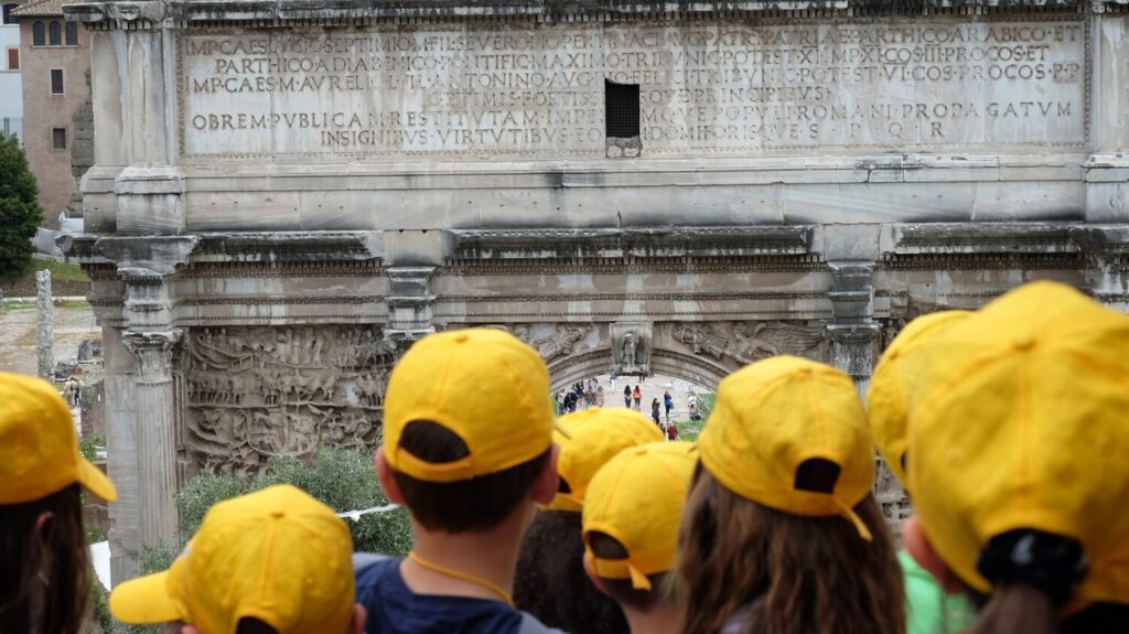 A group of tourists with yellow caps in Rome.