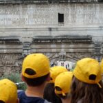 A group of tourists with yellow caps in Rome.