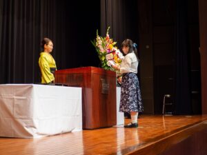 The Valedictorian of iCLA's graduating class delivers a speech in front of the Yamanashi Gakuin University President for the Fall Semester 2025 Graduation Ceremony.
