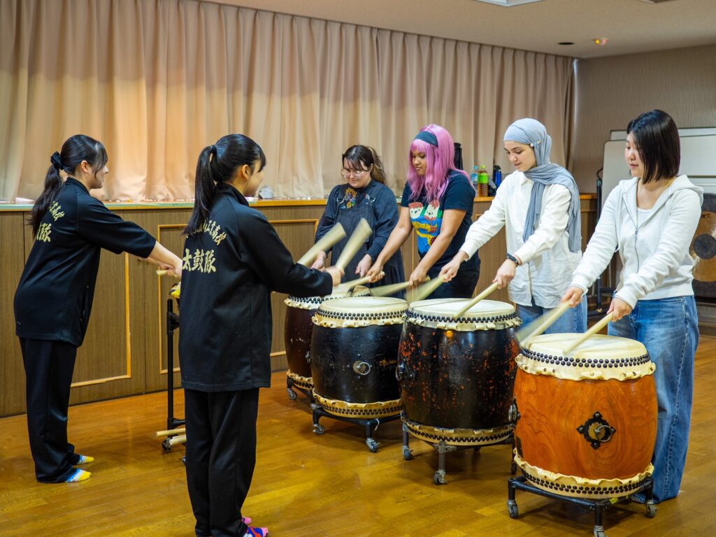 iCLA's international students try wadaiko, Japanese traditional drumming, under the tutelage of Nirasaki Kogyo High School's Taiko Club students.