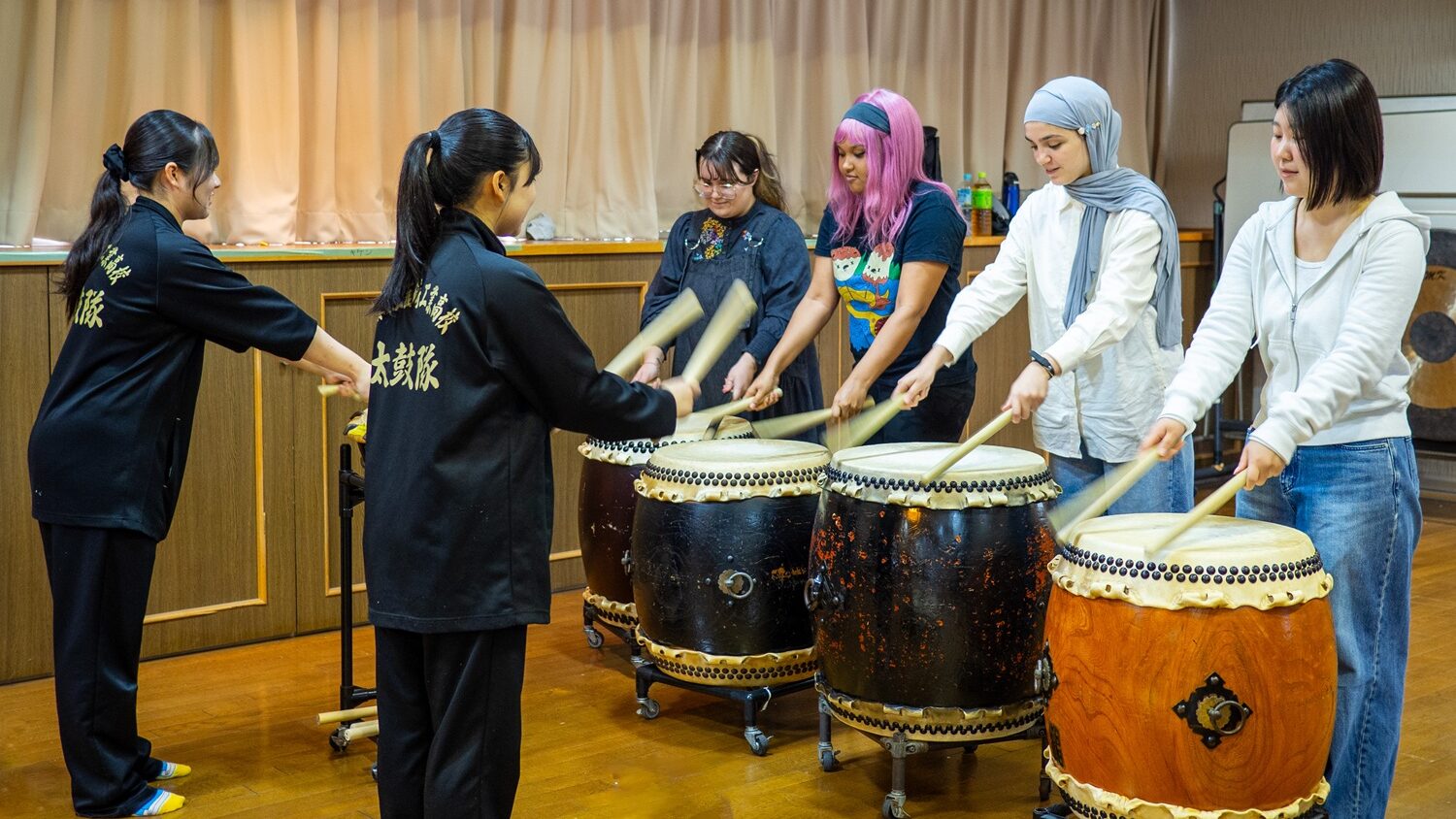 iCLA's international students try wadaiko, Japanese traditional drumming, under the tutelage of Nirasaki Kogyo High School's Taiko Club students.