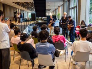 A band of iCLA students and faculty perform music in front of an audience at the Turquoise Blue cafeteria.