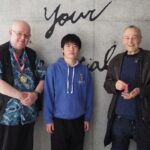 Dr. Darren Ashmore, Professor William Reed, and iCLA Alumnus Yamagishi are standing together, showing the Order of Scottish Samurai Medals.